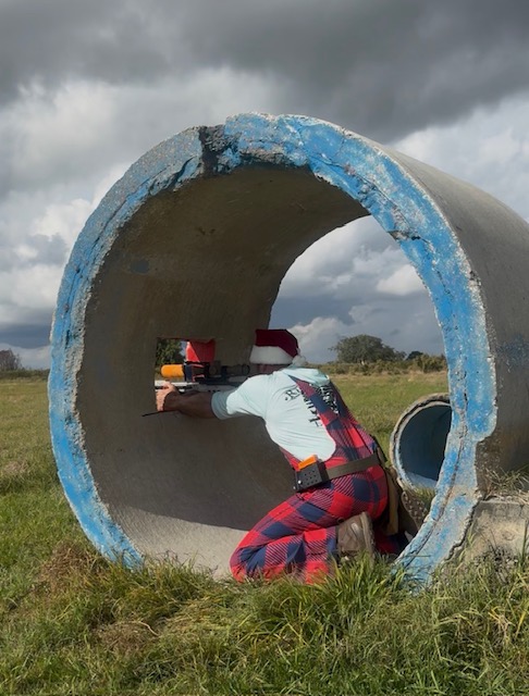 Precision rifle competitor building a supported position inside a concrete obstacle