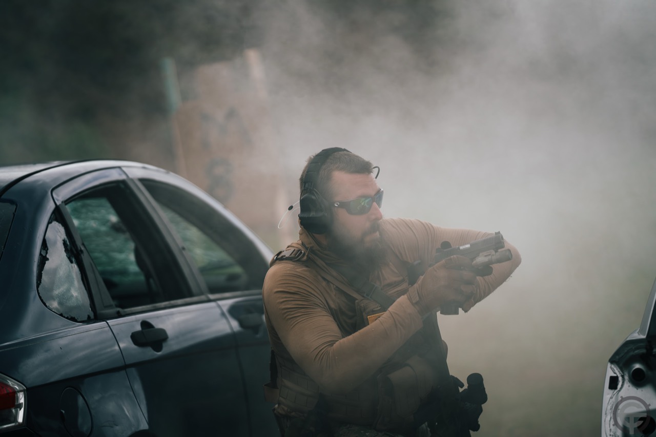 Shooter wearing eye and hearing protection moving between vehicles during a supervised defensive firearms course