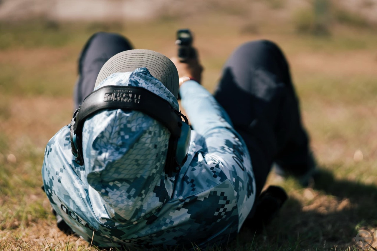 Shooter in eye and hearing protection practicing a prone pistol position